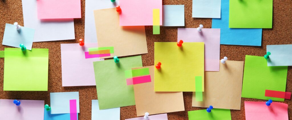 A collection of bright sticky notes stuck to a corkboard