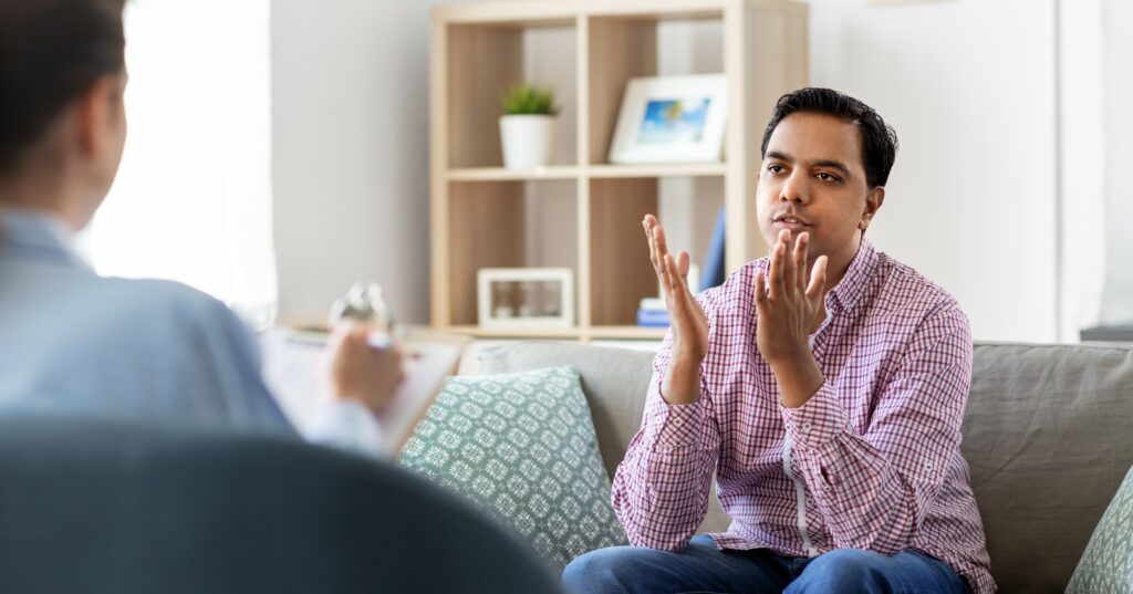 A man sits in a therapy session talking to his therapist