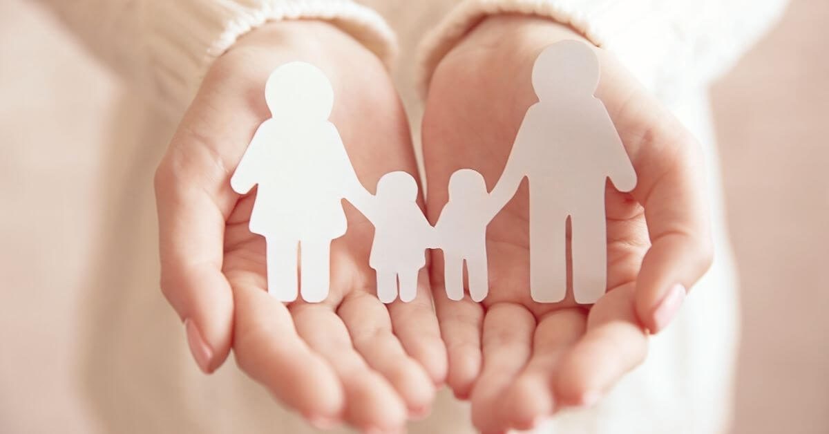 A woman holding paper cutouts of parents and children as a family.