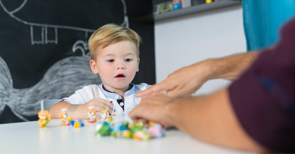 A little boy playing with some toys.