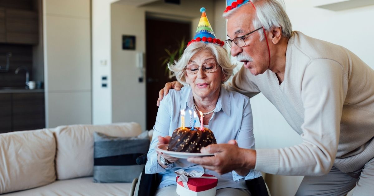 An elderly couple blowing out birthday candles.
