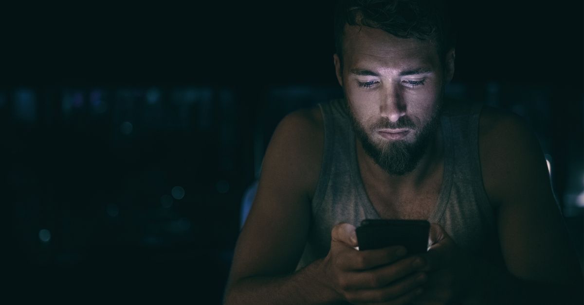 A man looking at his phone at night.