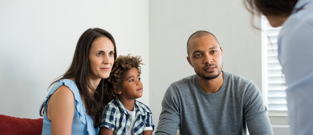 A couple and their son sit and talk to a counselor who sits out of frame