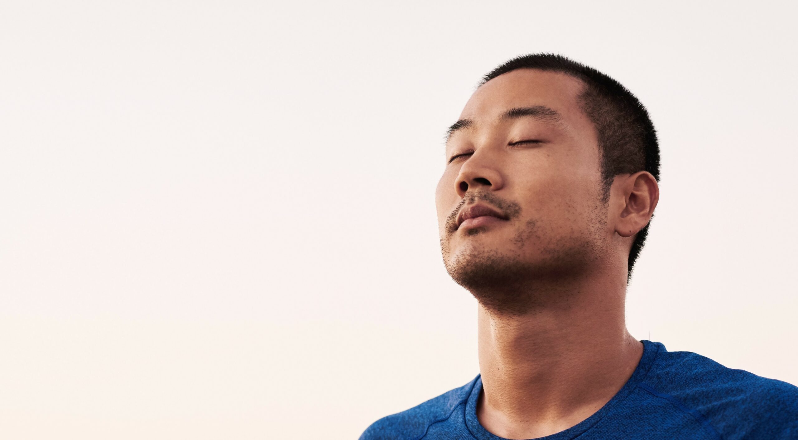 A man with eyes closed inhales through his nose and looks for calm