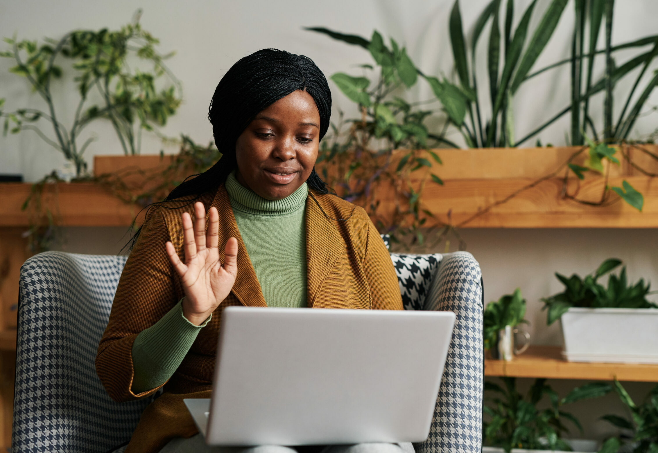 Therapist waves at telehealth patient on her laptop