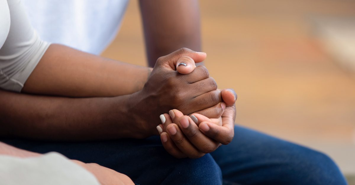 A couple holding hands and grieving together.