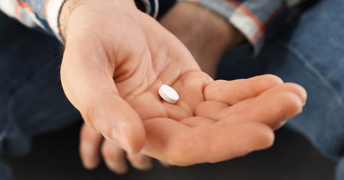 A man holding an antidepressant pill in his hand.