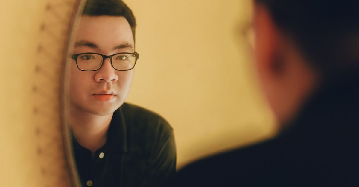 A man looking at his reflection in a mirror.