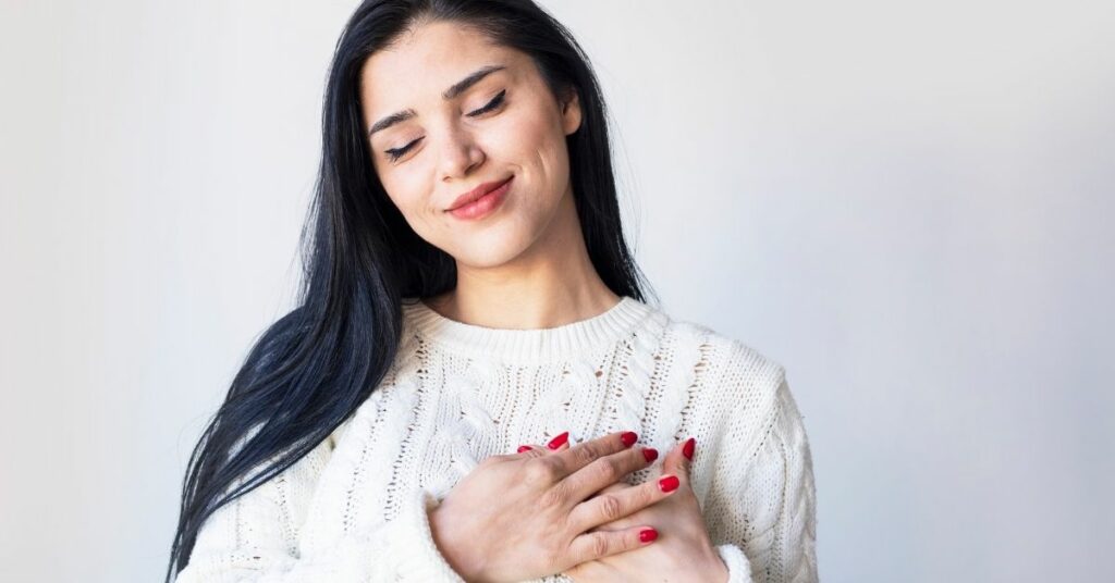 A woman with her hands over her heart.