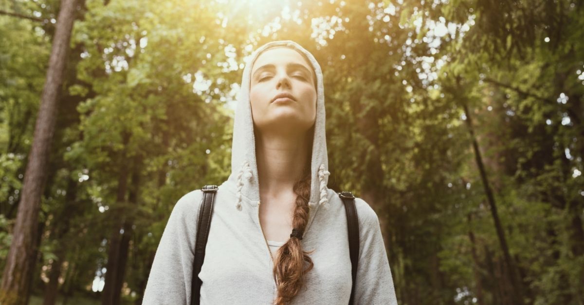 A woman taking a mindfulness walk in a forest.