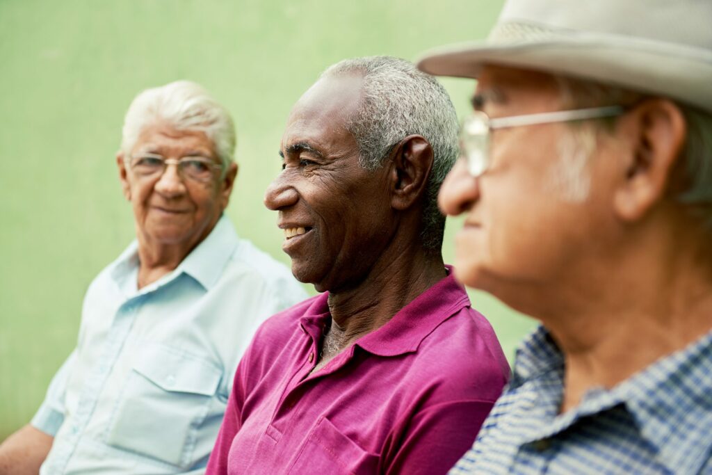 three senior men sitting on bench