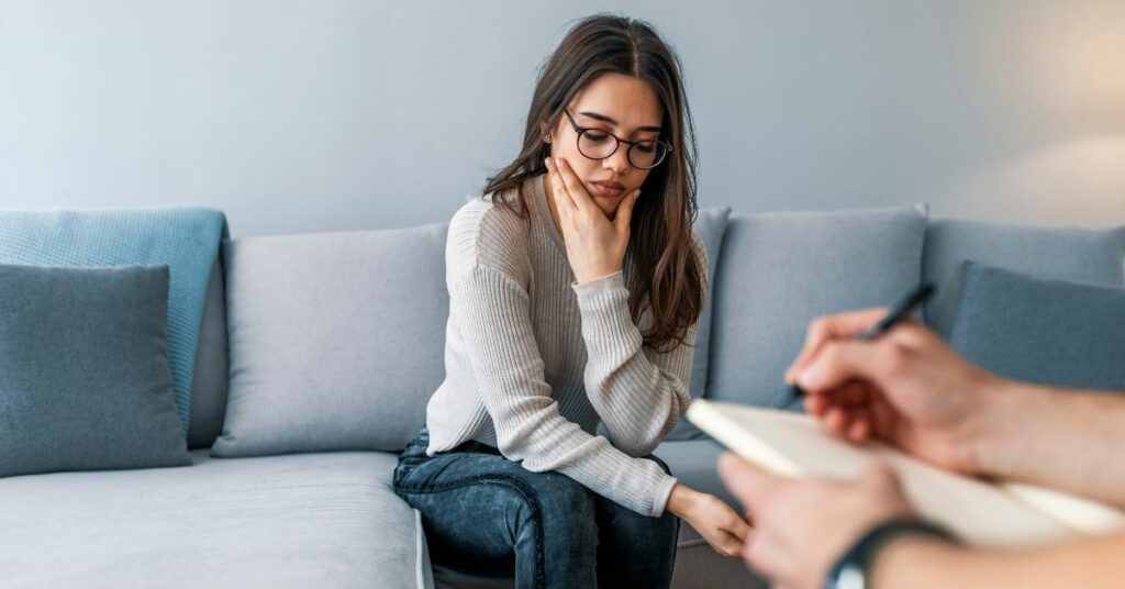 A woman looking sad in a therapy session.
