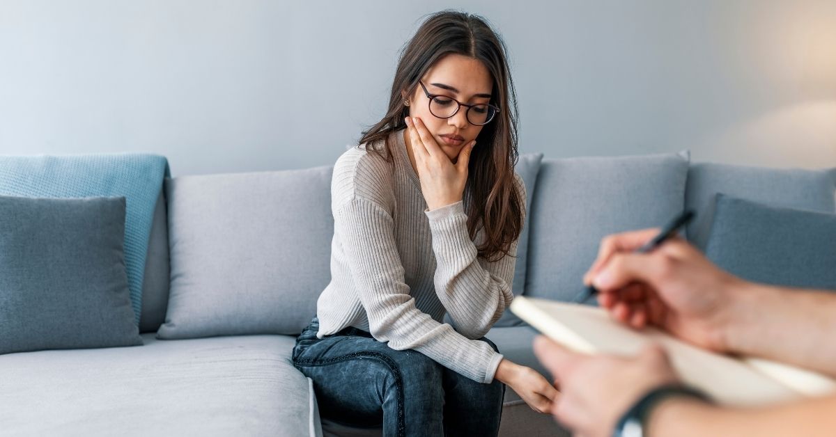 A woman looking sad in a therapy session.
