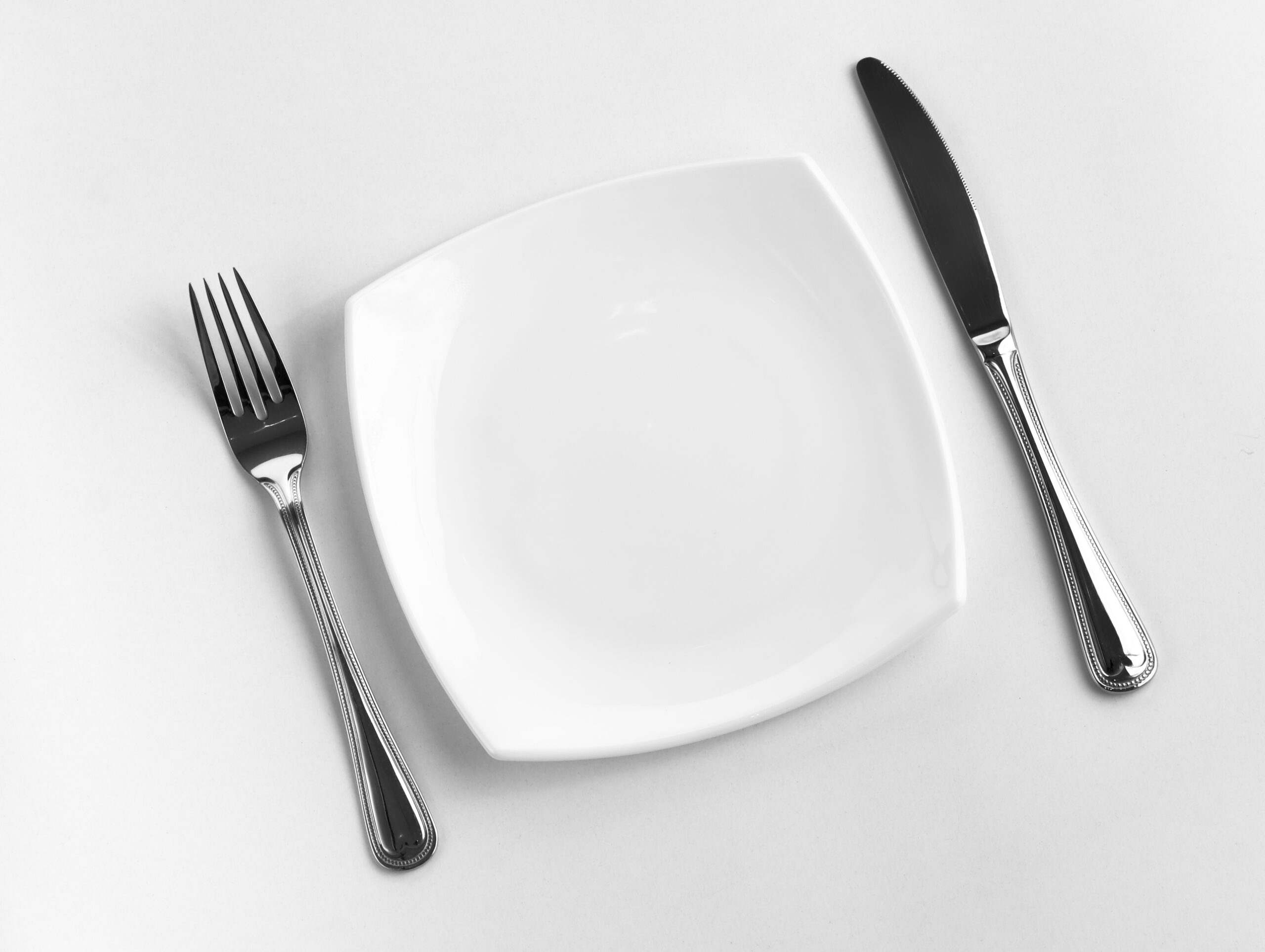 Empty white plate with fork and knife
