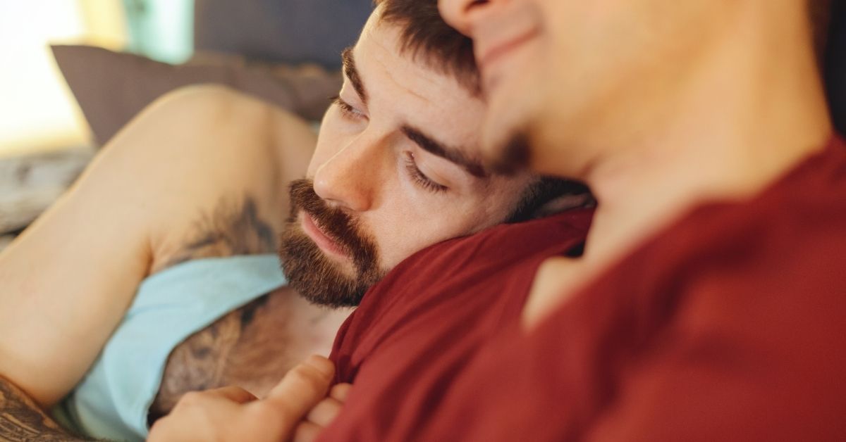 A male couple cuddling on the couch.