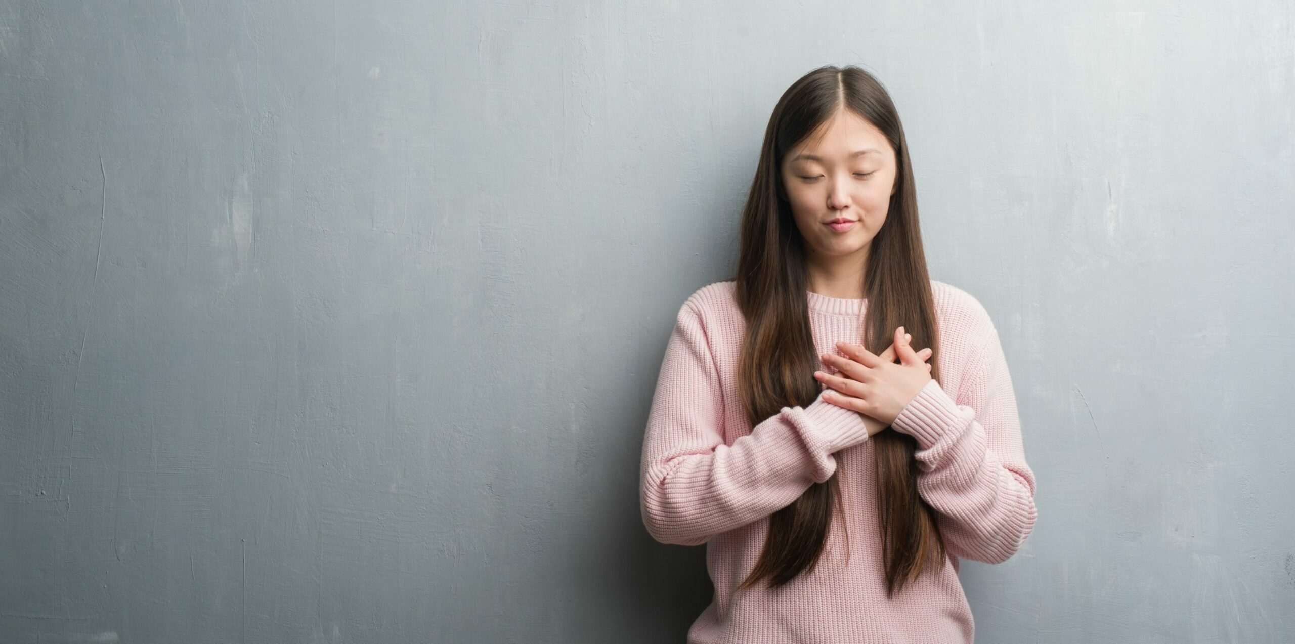 woman-in-pink-sweater-with-hand-over-heart