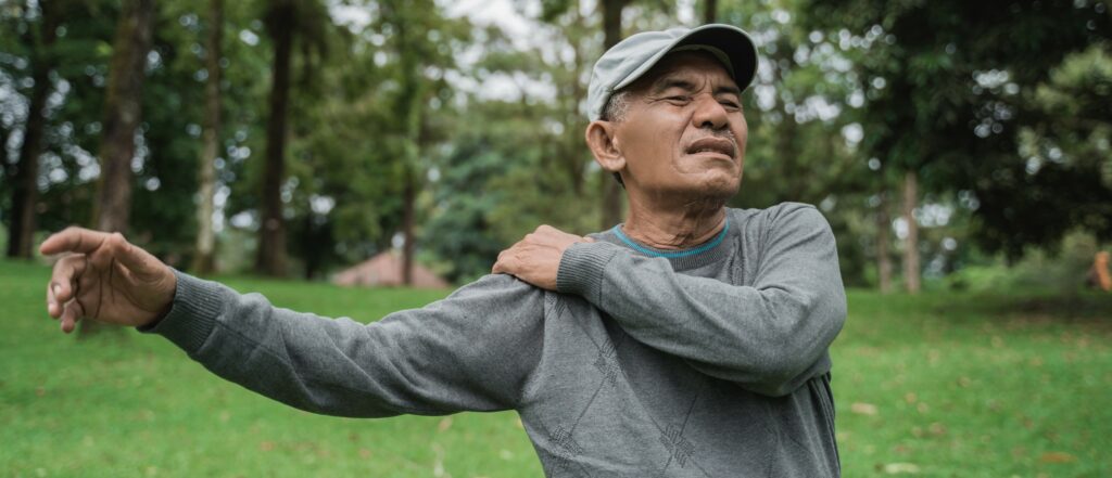 An older man grabs his shoulder in pain
