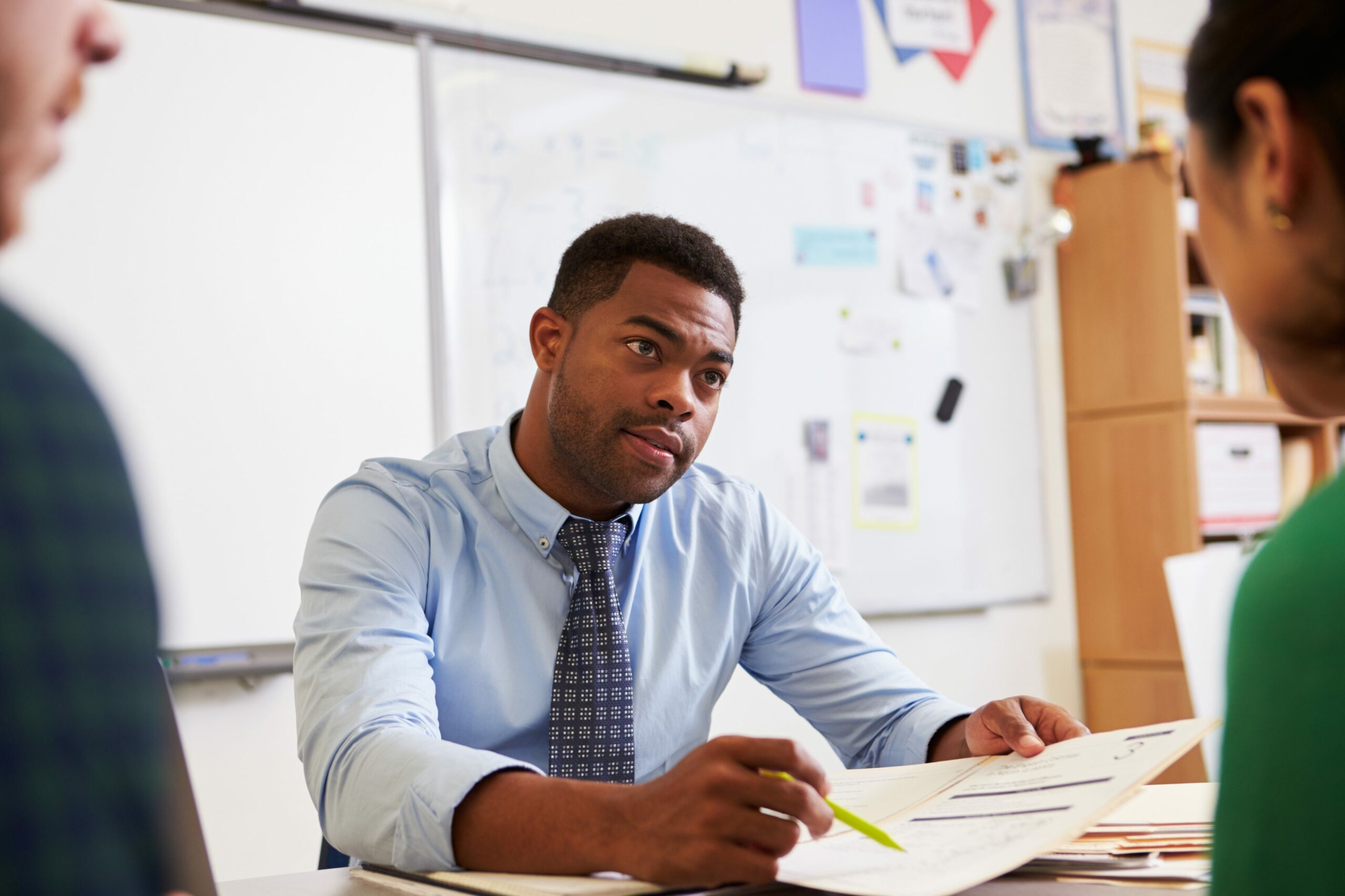 Concerned teacher goes over a report while sitting at his desk