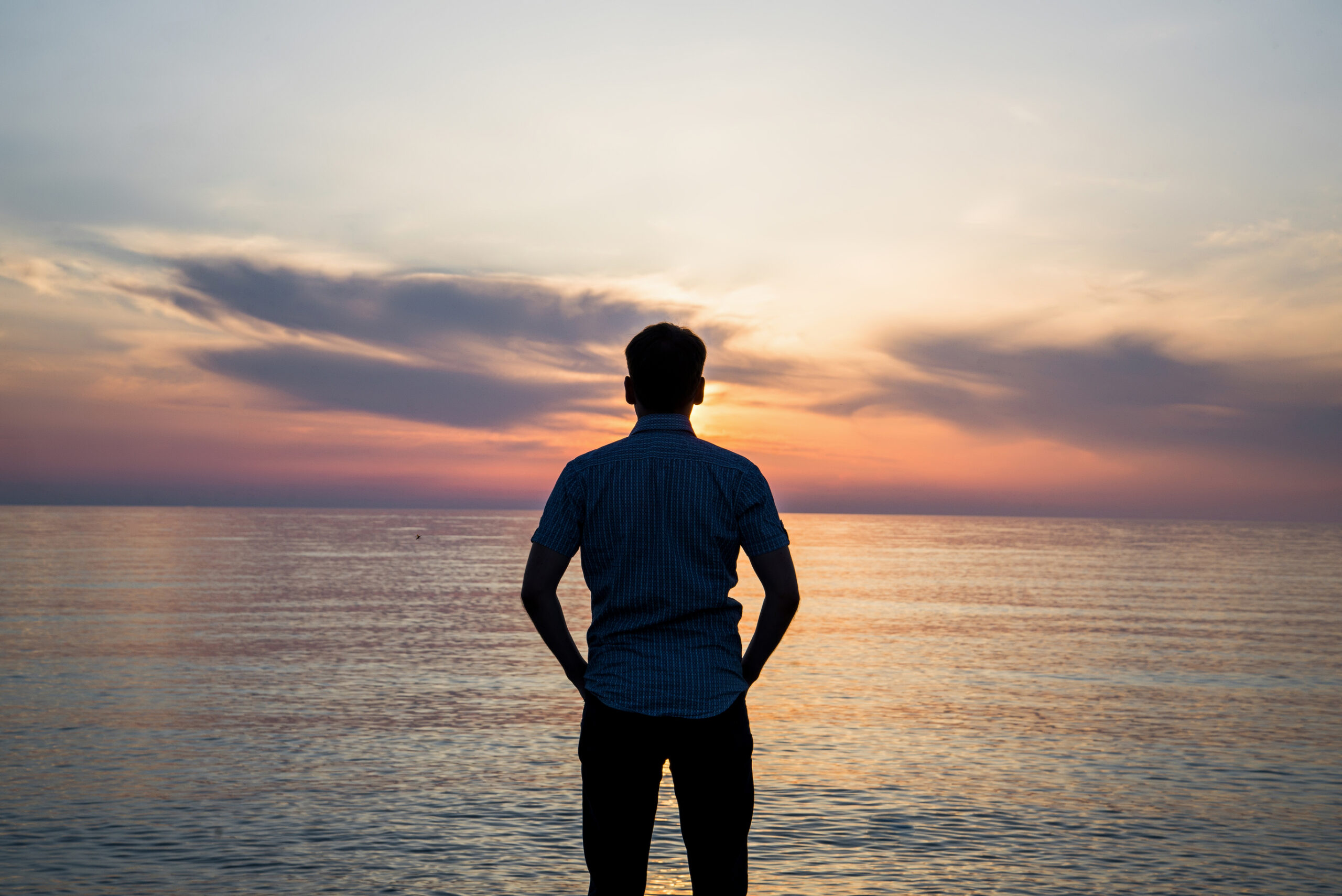 Man looking at sunset over ocean