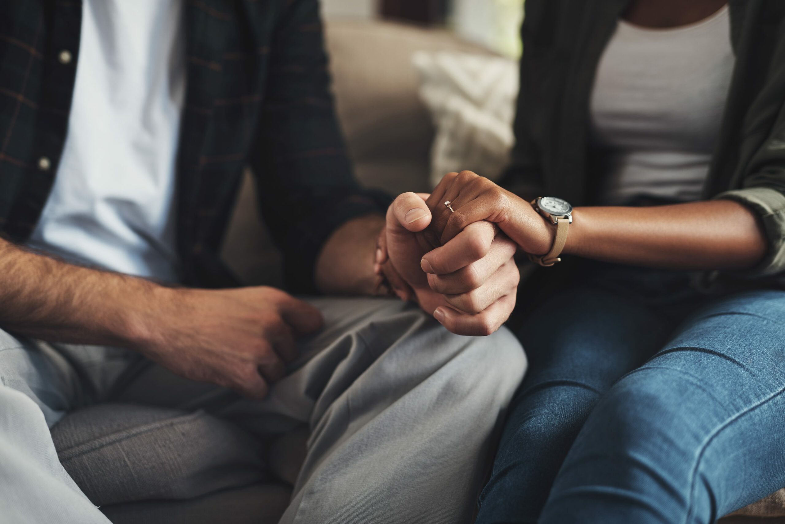 closeup-couple-holding-hands-on-sofa
