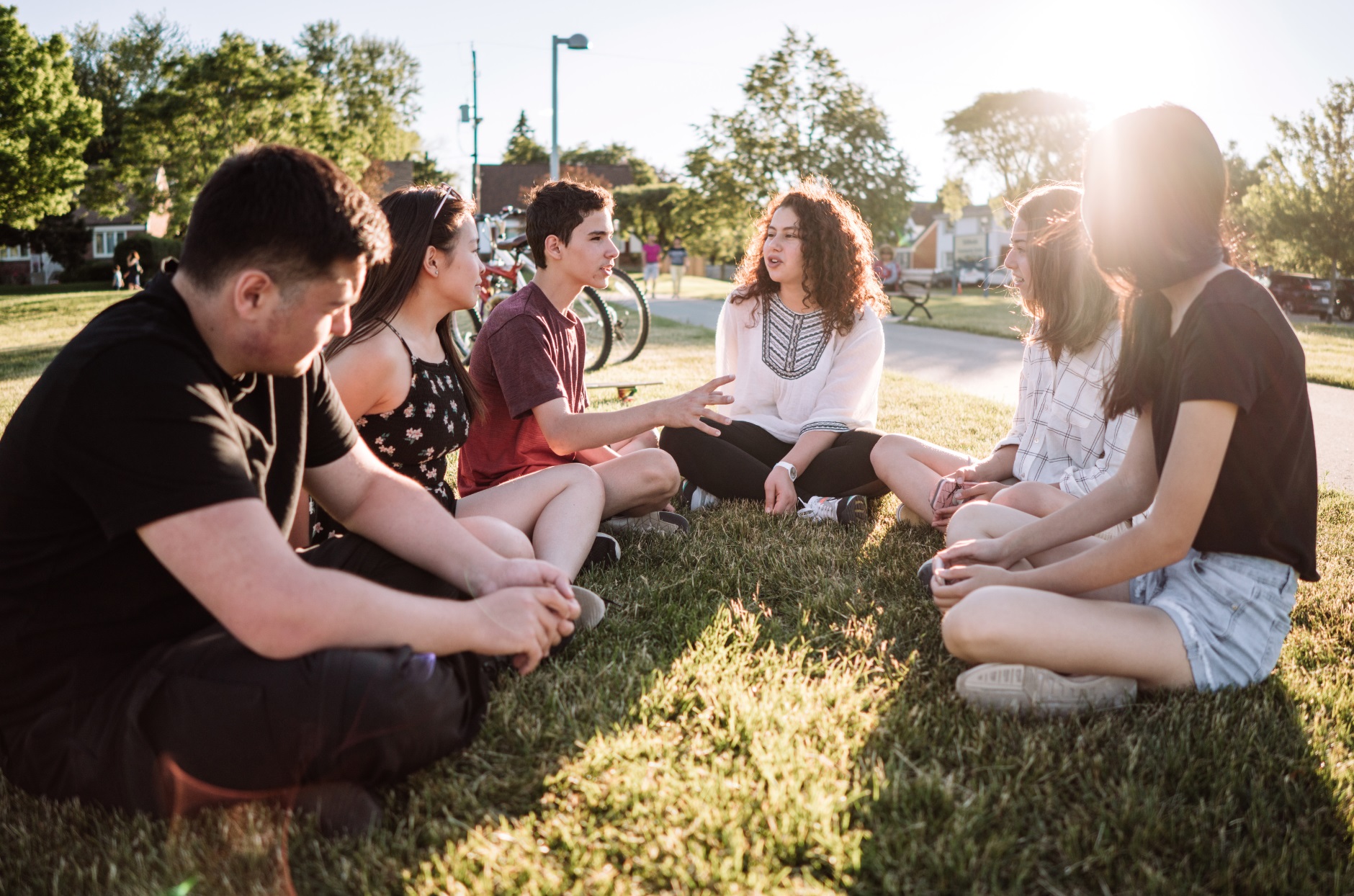 Teens sitting outside in a circle on the ground