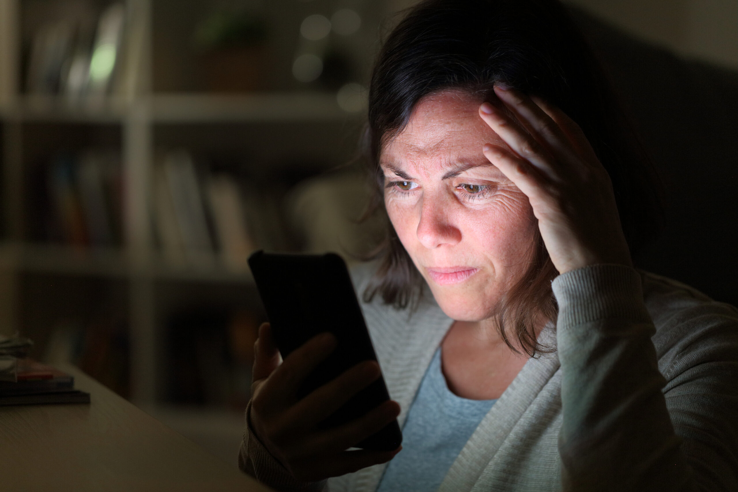 Concerned woman stares at screen of smart phone