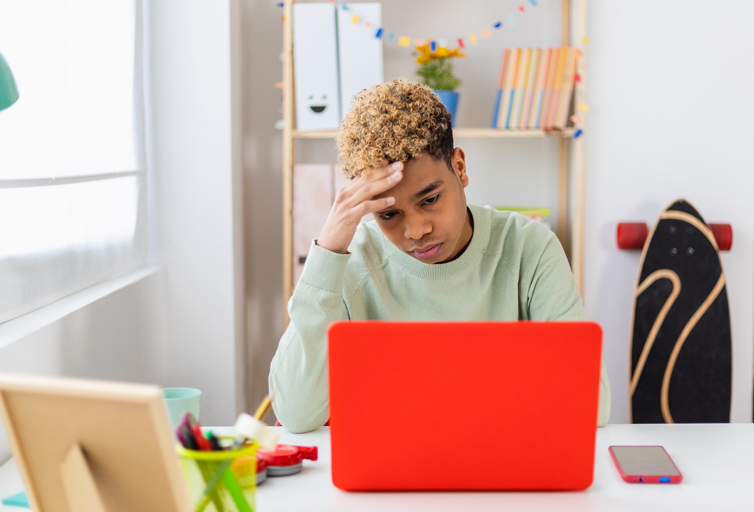 stressed teen boy sitting in front of laptop