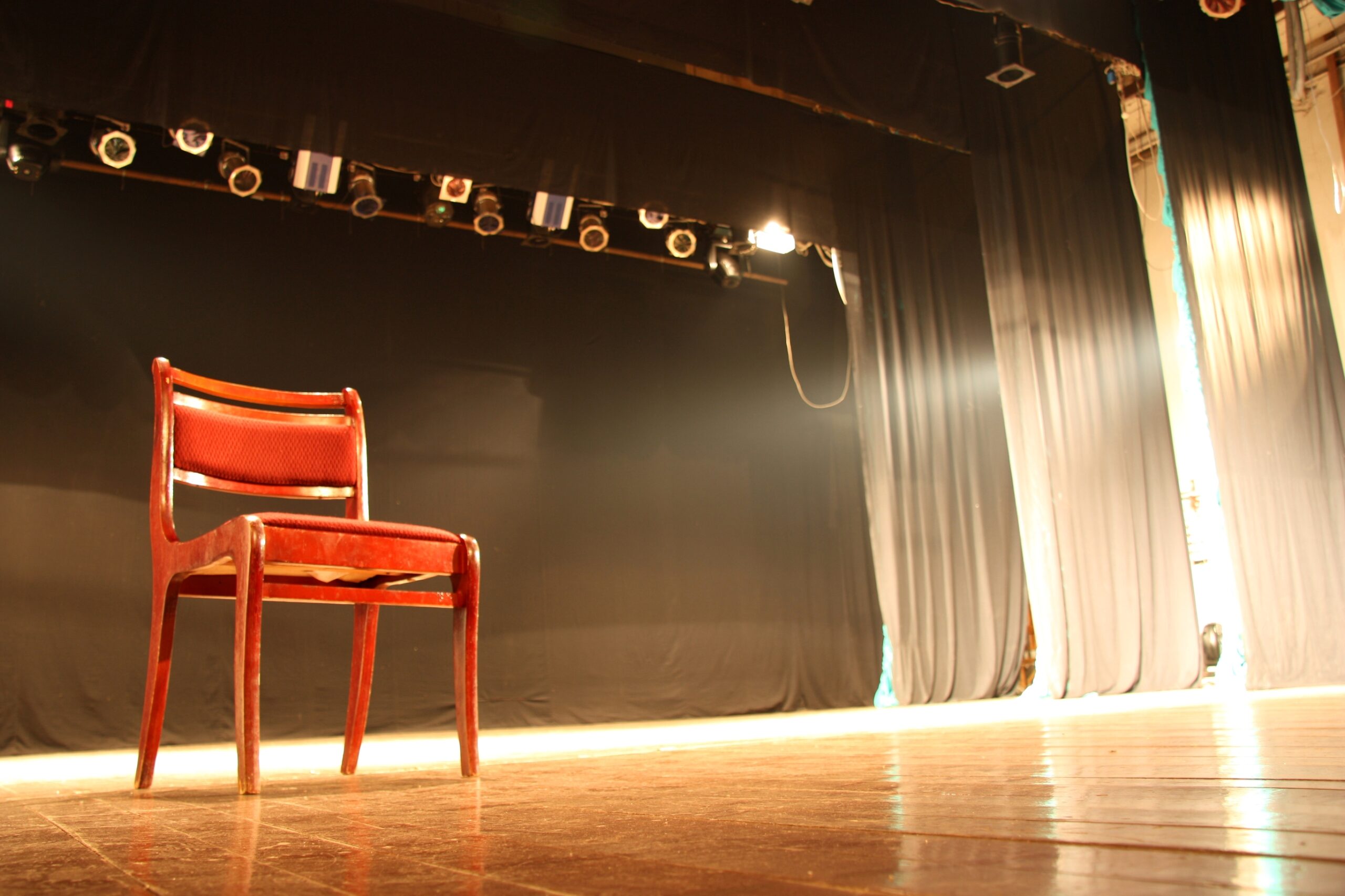 empty wooden chair on empty lit stage