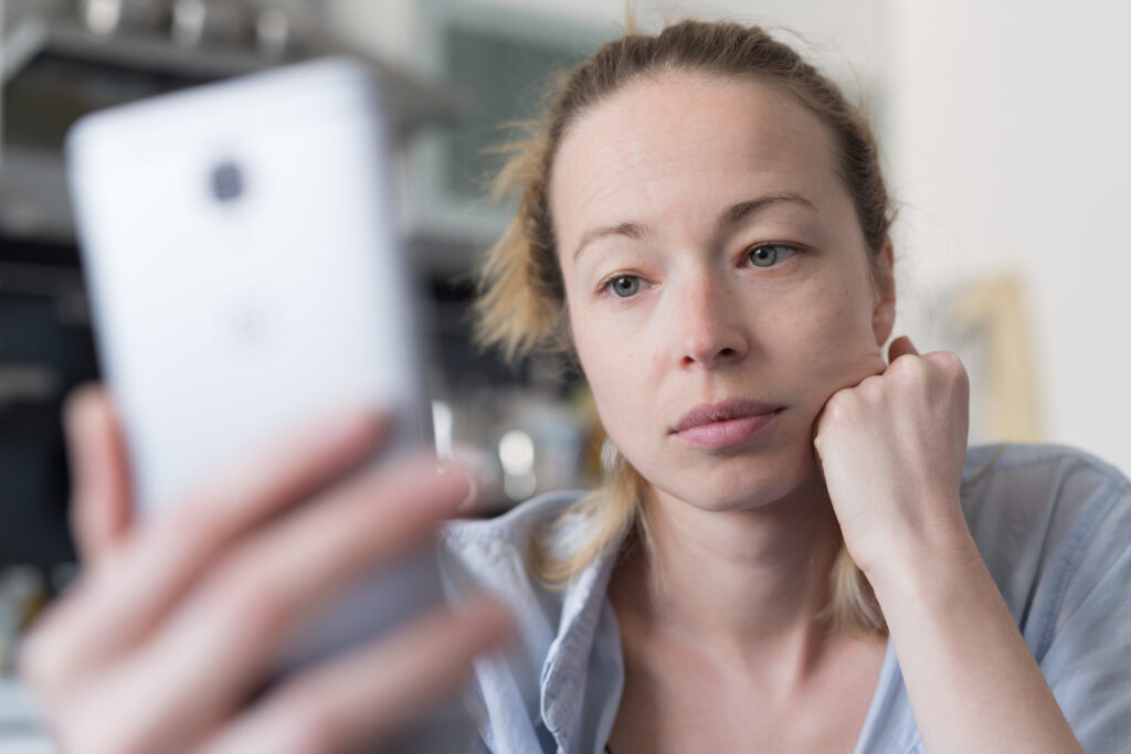 A worried woman stares at her phone