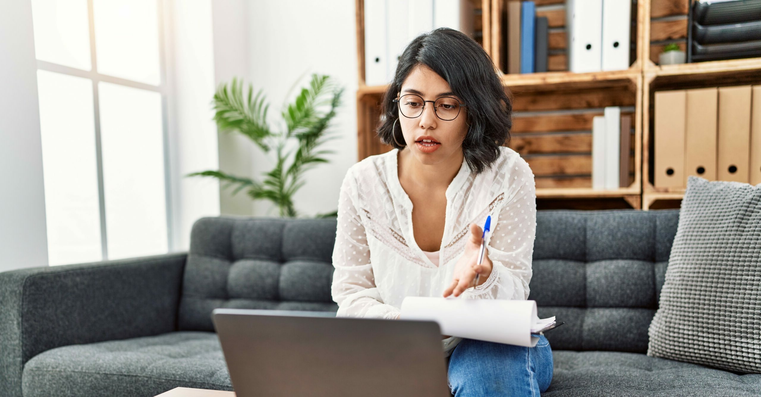 A woman video chats on her laptop while taking notes