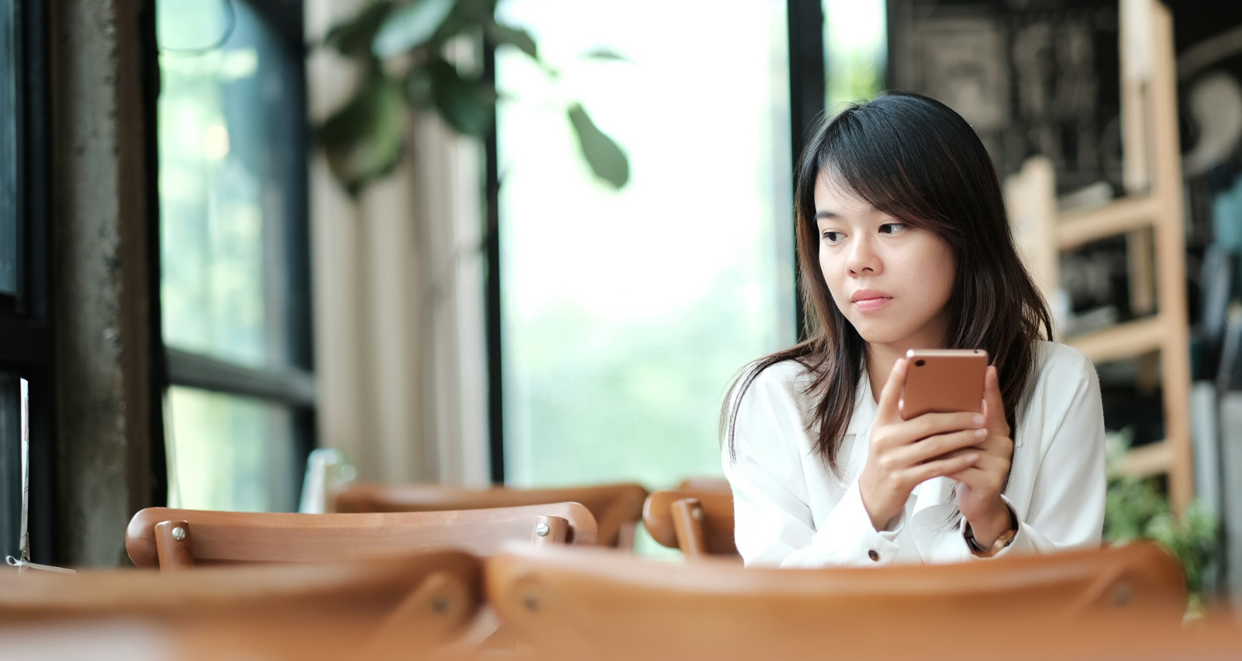A woman holds a phone and looks away dejected