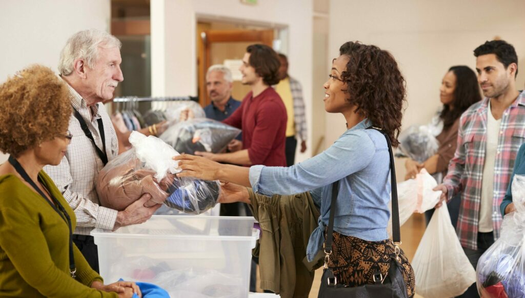 People hand bags of clothes to volunteers at a clothing drive