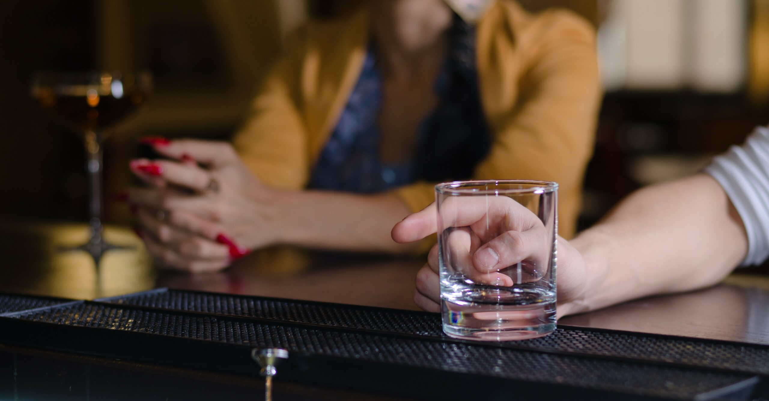Image of a bar with two sets of hands and an obscured face in the background