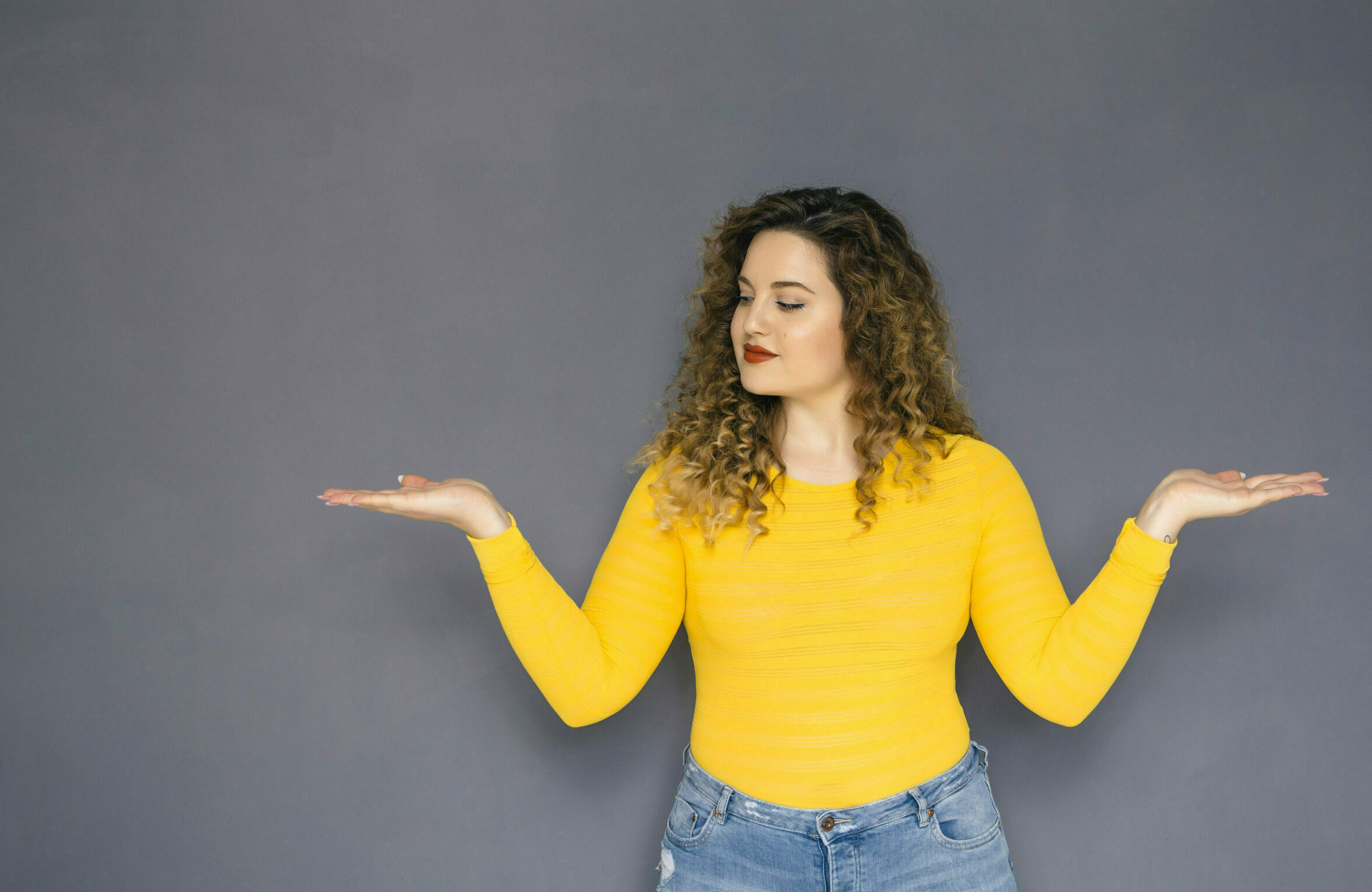 brunette-woman-in-yellow-shirt-with-hands-raised-at-shoulder-level-scaled.jpg