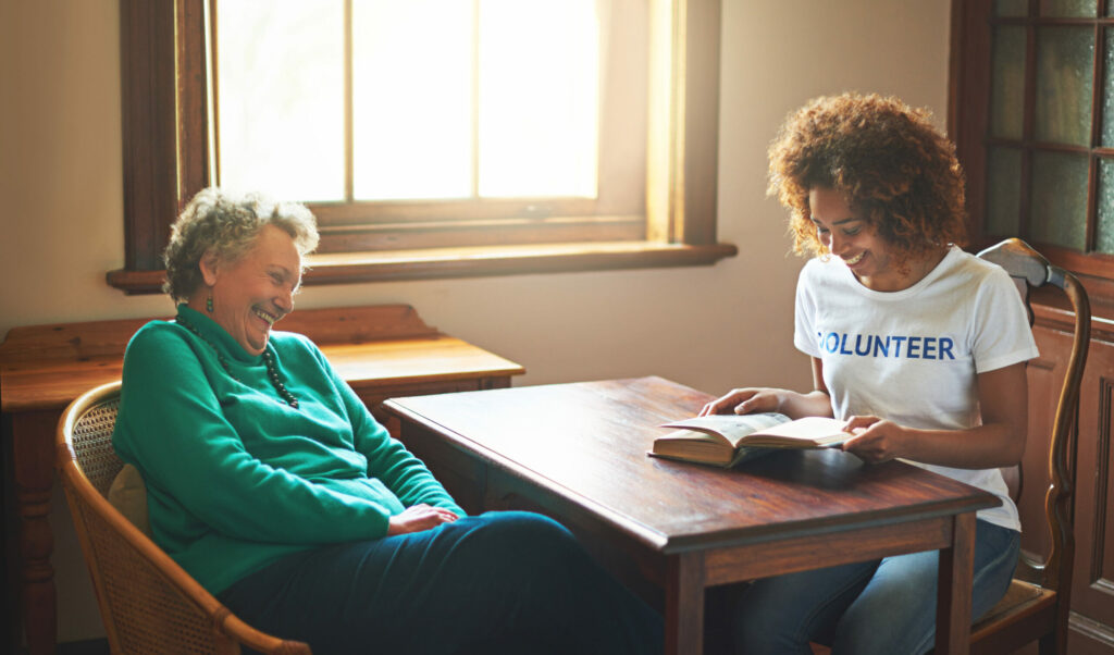 Young woman volunteer reads to senior woman