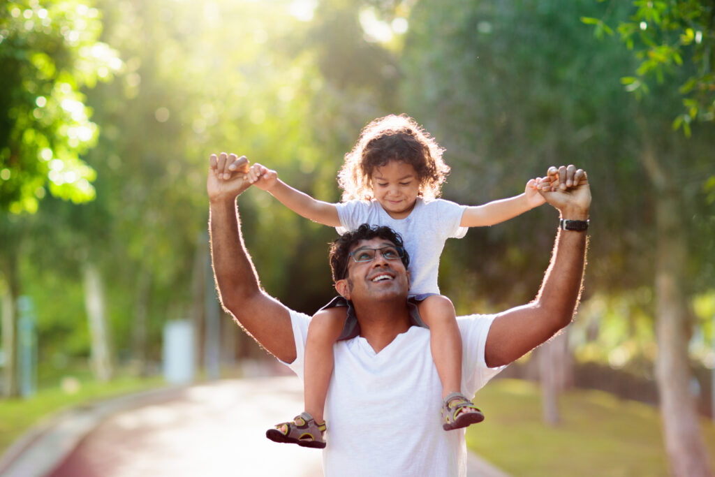 Young child on father's shoulders in a park