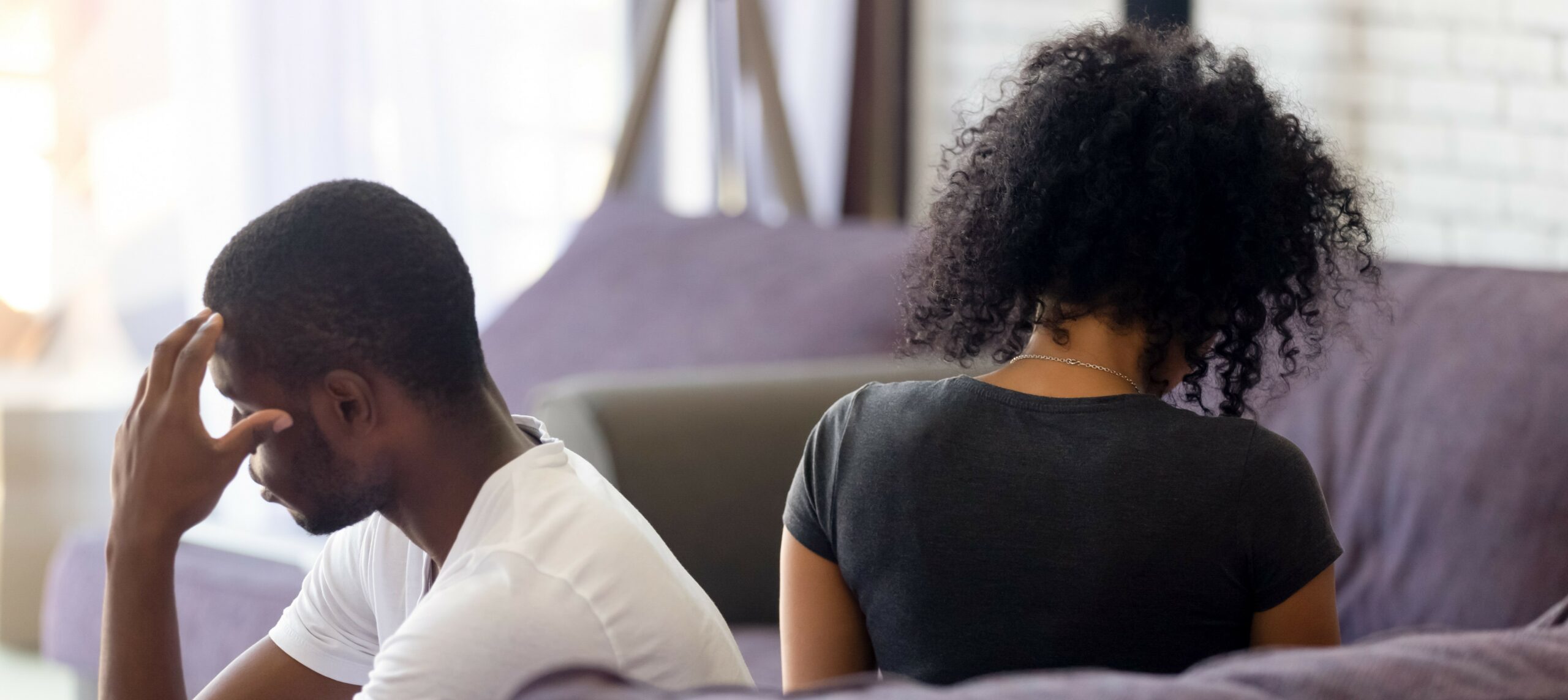 View from behind of a couple sitting on a couch facing opposite directions