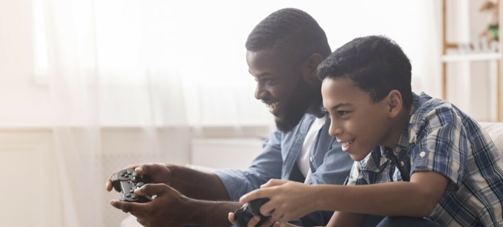 A father and son sit on a couch playing video games together