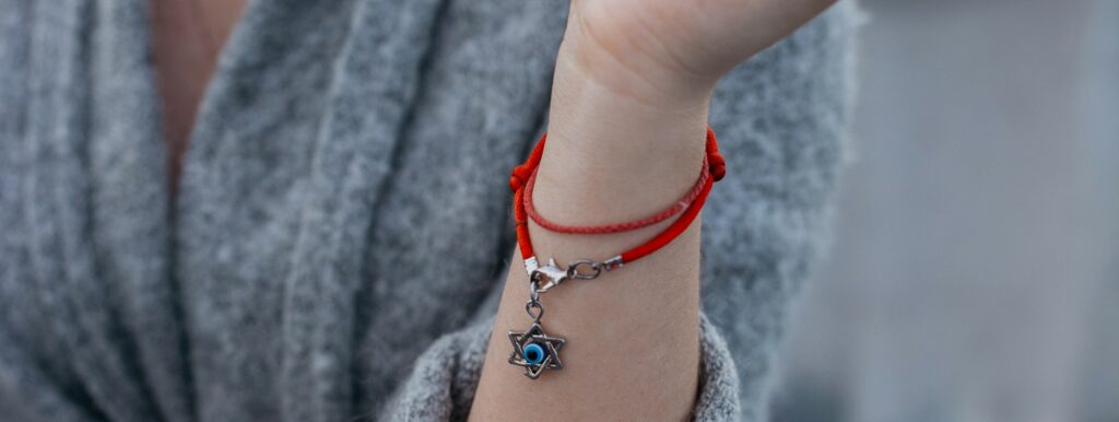 A necklace with the Star of David wraps around the wrist of a woman wearing a cardigan