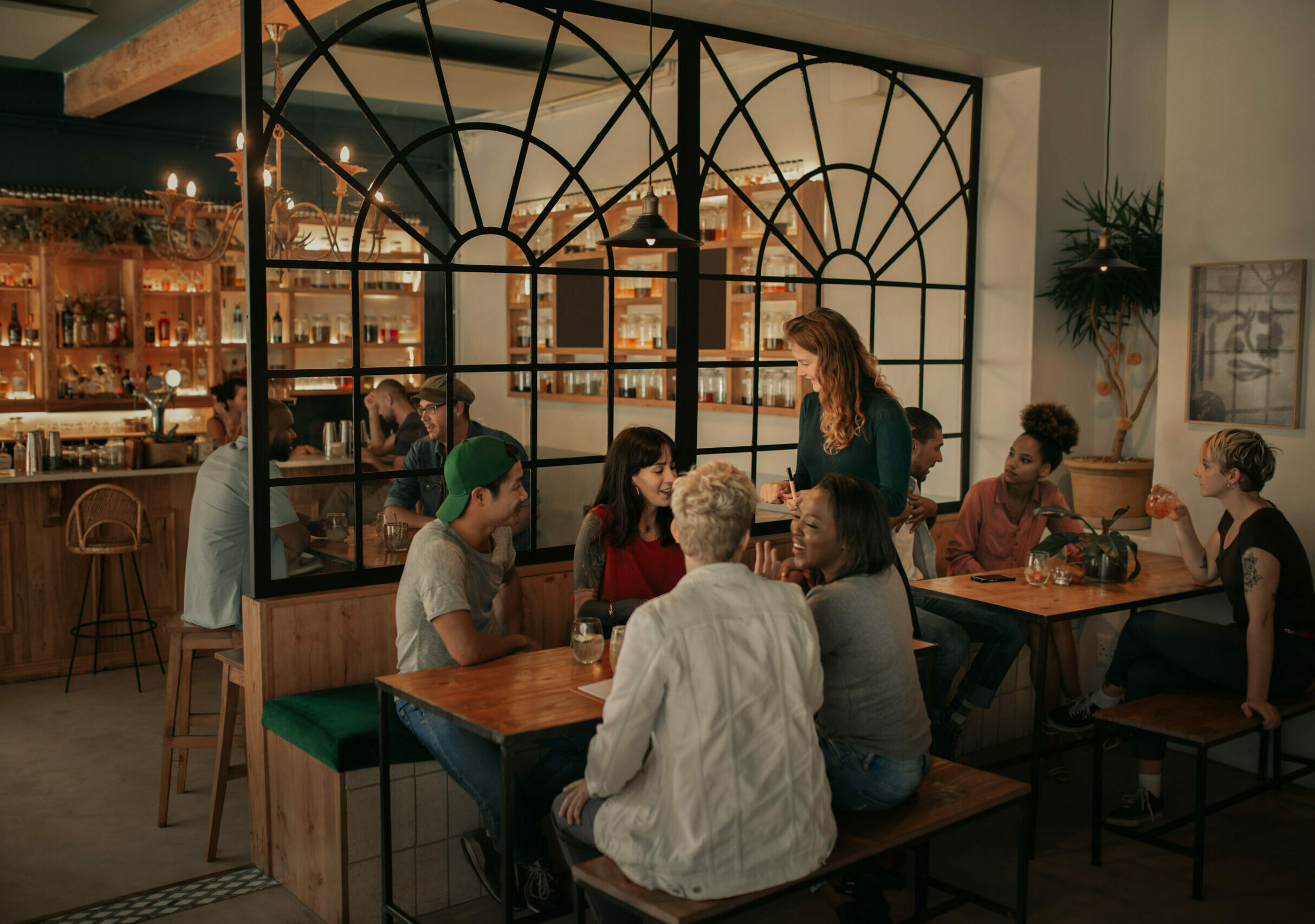 A group of young people ordering drinks at a restaurant with a bar